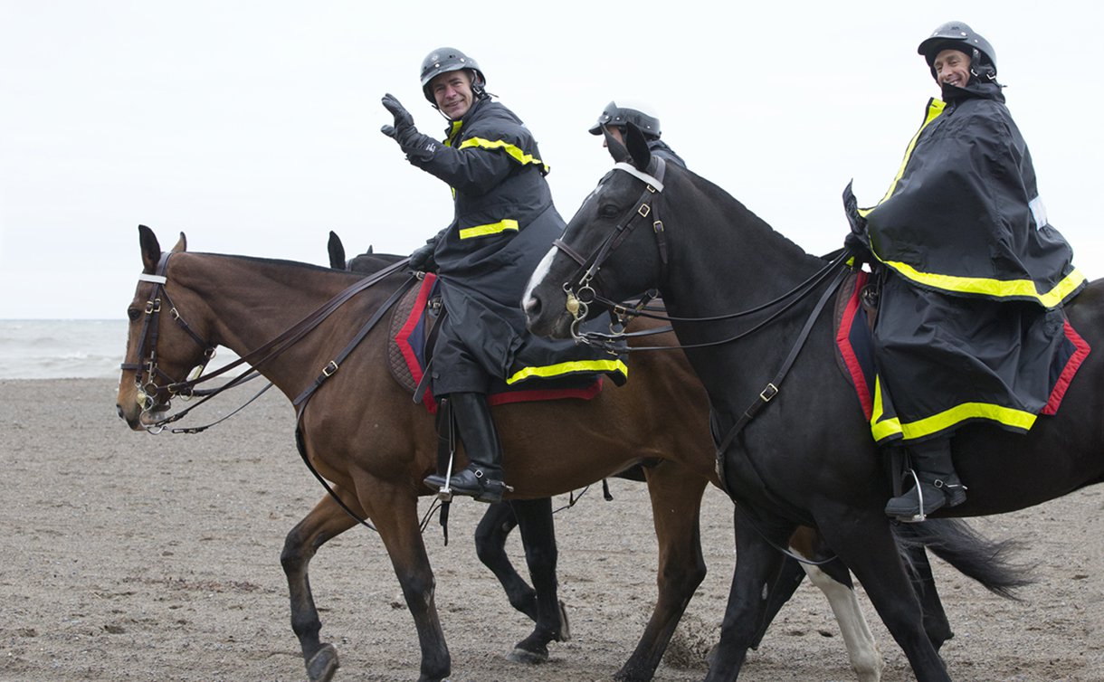 A man in TPS uniform on horseback waves