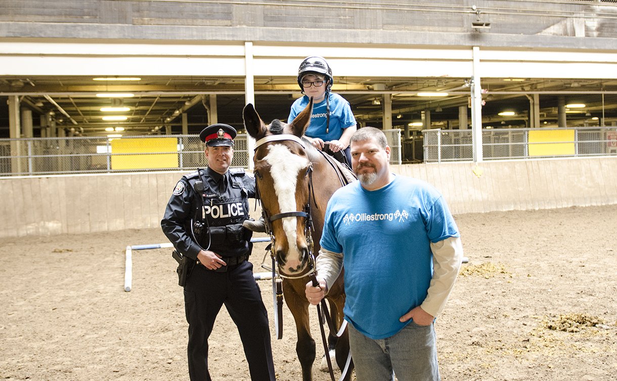 A man in TPS uniform beside a boy on a horse with a man holding the reins