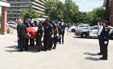 A group of police officers carries a coffin