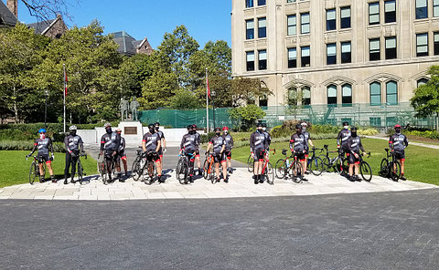 A group of cyclists in front of a memorial