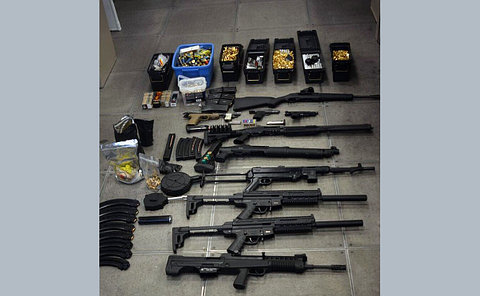 A large quantity of ammunition, guns and drugs laying on the floor.