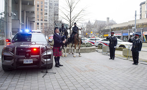 A piper, officers on horseback and two officers saluting