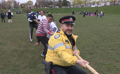 A man in TPS uniform pulling on a rope with kids