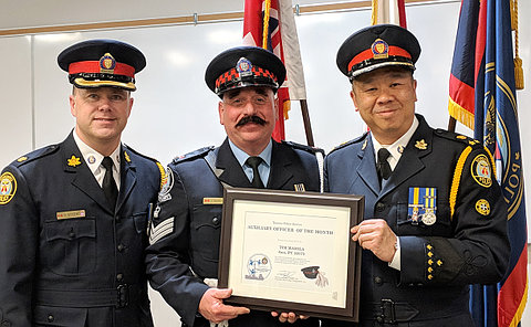 Three men in TPS uniform, one holds certificate