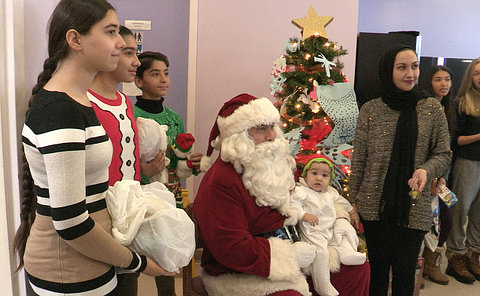 A Santa holding a baby with others standing for a photo