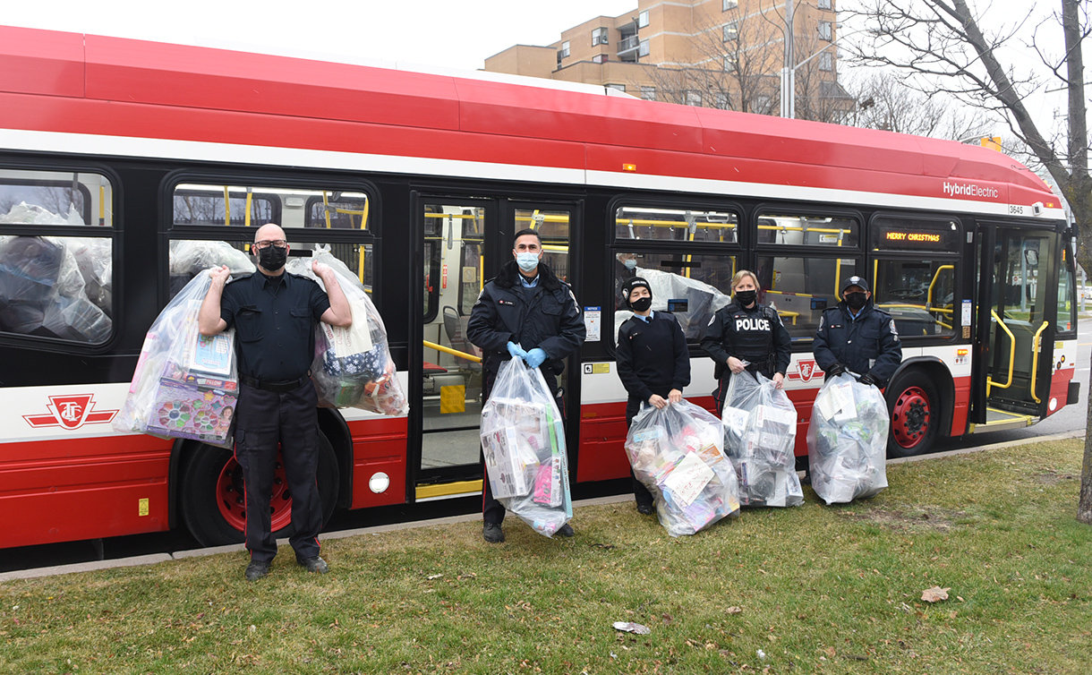 A group of people holding large bags in front of bus