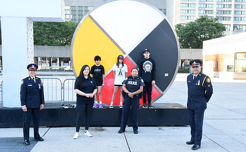 A group of people, some in TPS uniform in front of a large medicine wheel