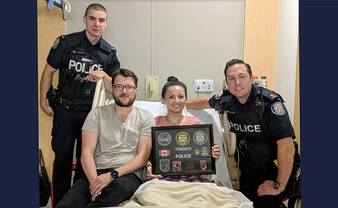 Two men in TPS uniform with a man and woman in a hospital bed