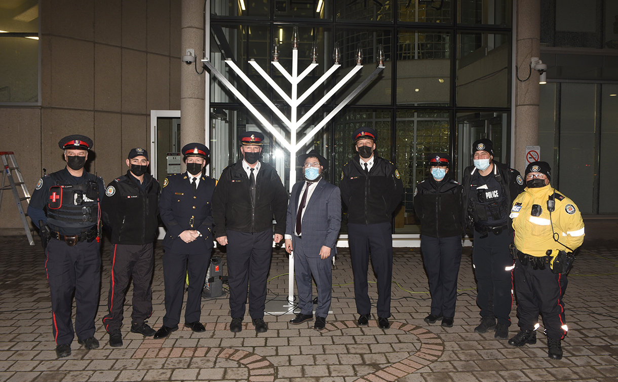 A group of police officers standing in front of large menorah