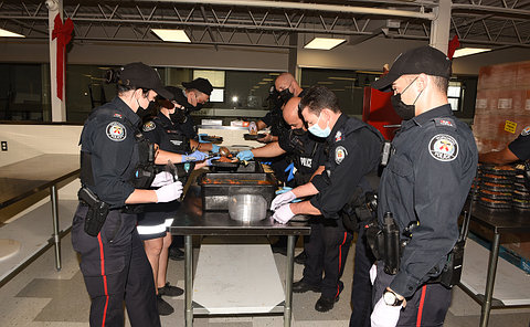 A group of officers packing meals into containers