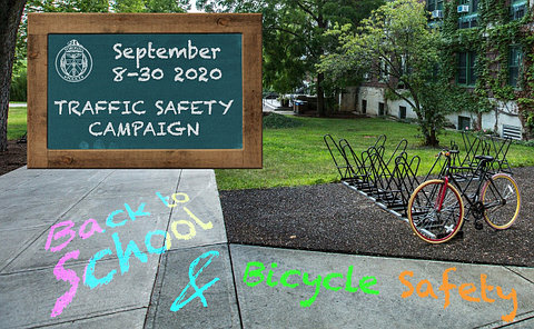 A bicycle on a rack with chalk on sidewalk "back to school" and "bicycle safety"