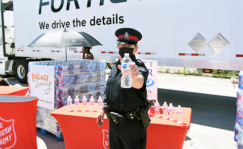 Man in a police uniform holding a bottle of water in front of him.