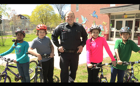 A man in TPS uniform with four children wearing helmets on bicycles