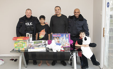 Two men in TPS uniform with two boys and a man with a table of toys