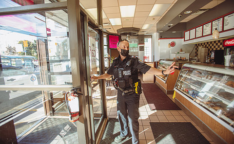 A police officer waves at a doorway