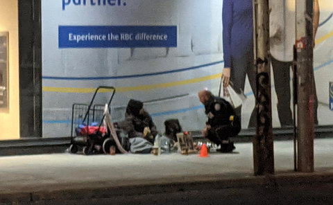 A man in TPS uniform crouches beside a person