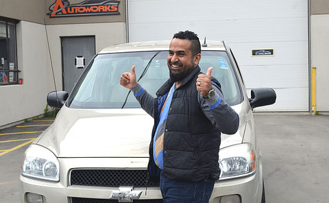 A man giving thumbs up beside a minivan
